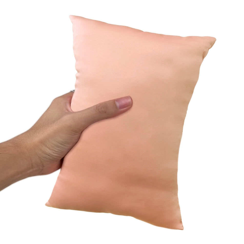 A hand holding a peach colored, mini-sized, travel pillow.