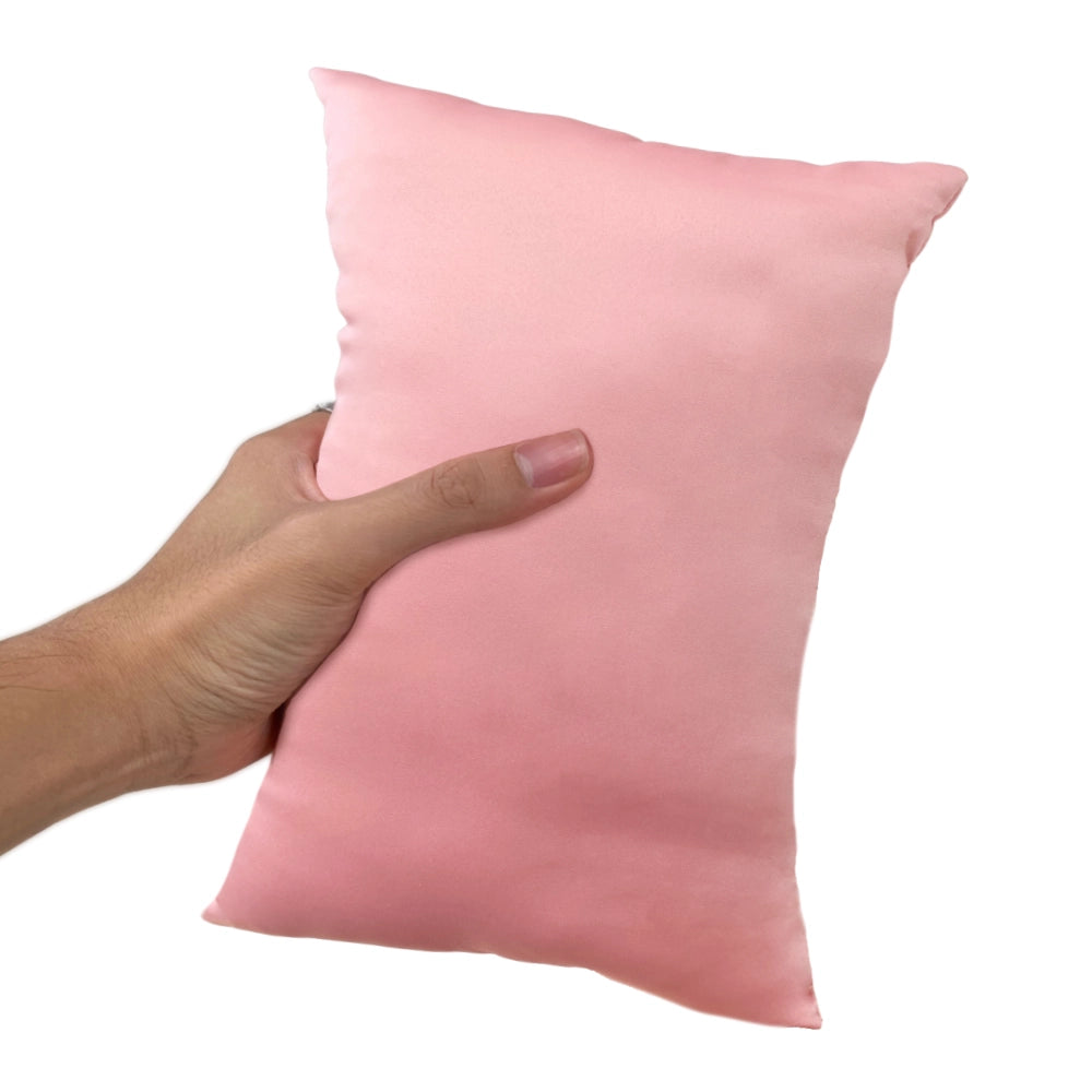 a hand holding a pink, mini-sized travel pillow